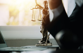 business and lawyers discussing contract papers with brass scale on desk in office