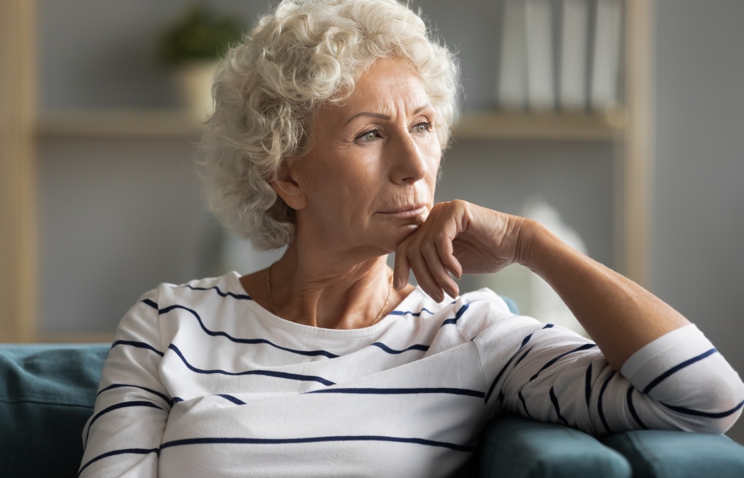 Pensive middle-aged old lady sit on couch at home look in distance thinking pondering, thoughtful unhappy elderly woman lost in thoughts missing remembering past, feeling lonely, solitude concept Martinez, GA