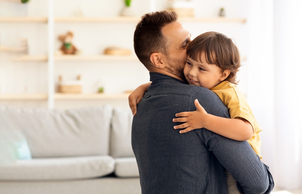 Cute little boy enjoying time with loving daddy, caring man embracing and kissing his lovely son, holding him on hands at home interior Martinez, GA
